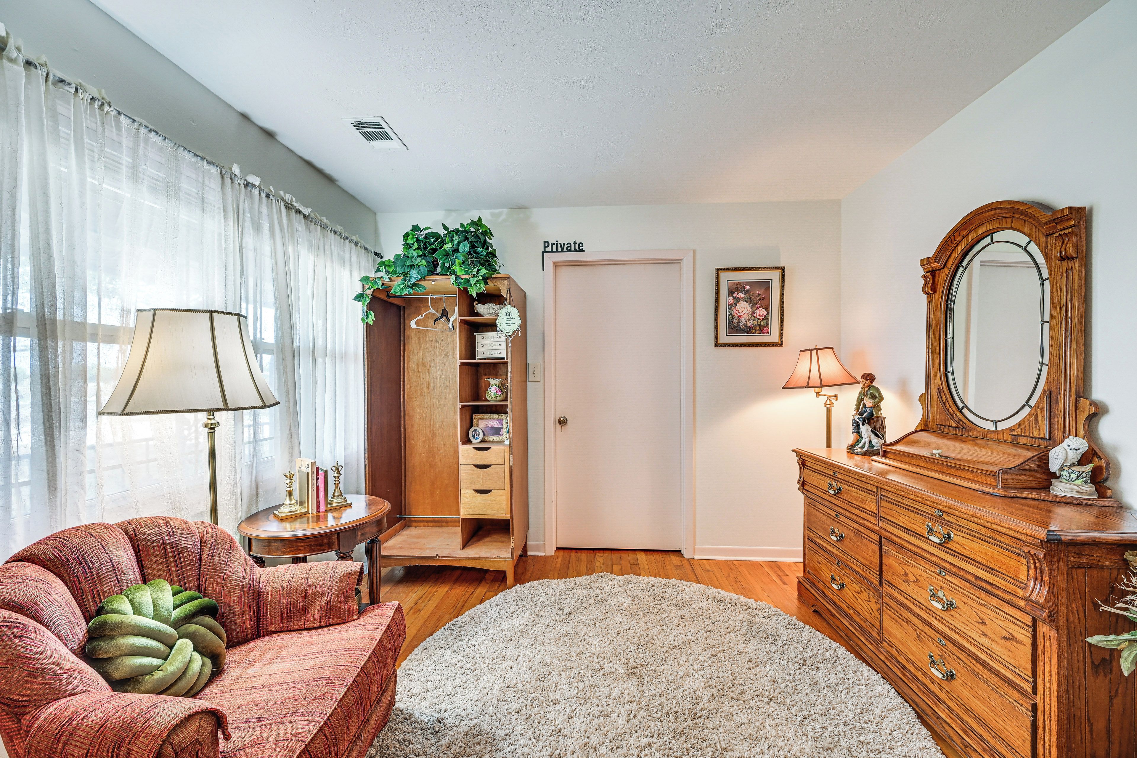 A room with a sofa, a wooden dresser, a mirror, a lamp, a bookshelf, and a door labeled 'Private.'