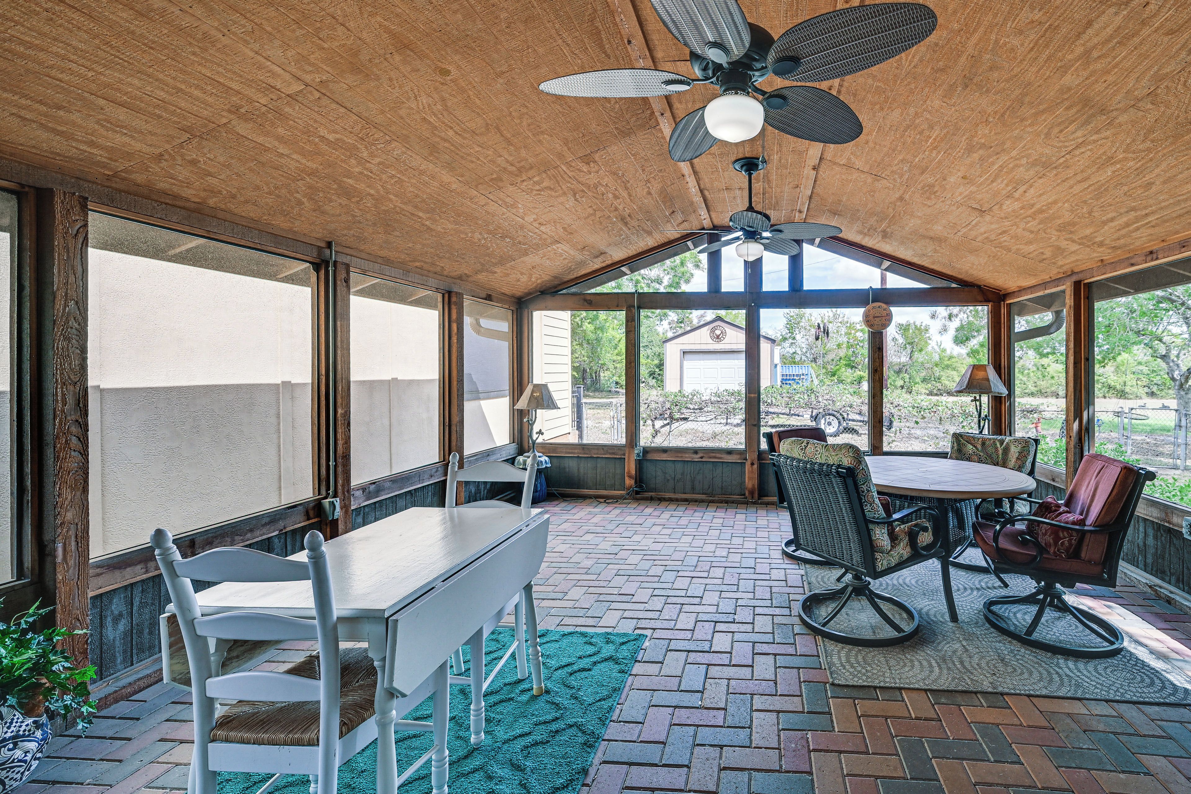 A covered patio area with a table and chairs, a ceiling fan, and a view of the outdoors.