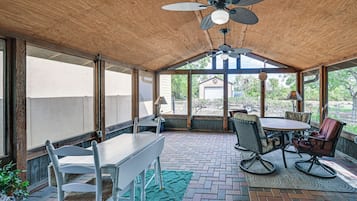 A covered patio area with a table and chairs, a ceiling fan, and a view of the outdoors.