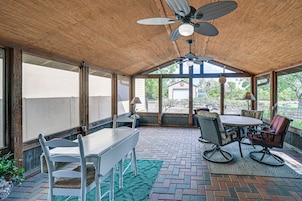 Área de varanda coberta com mesa, cadeiras, ventilador de teto e vista para o exterior.