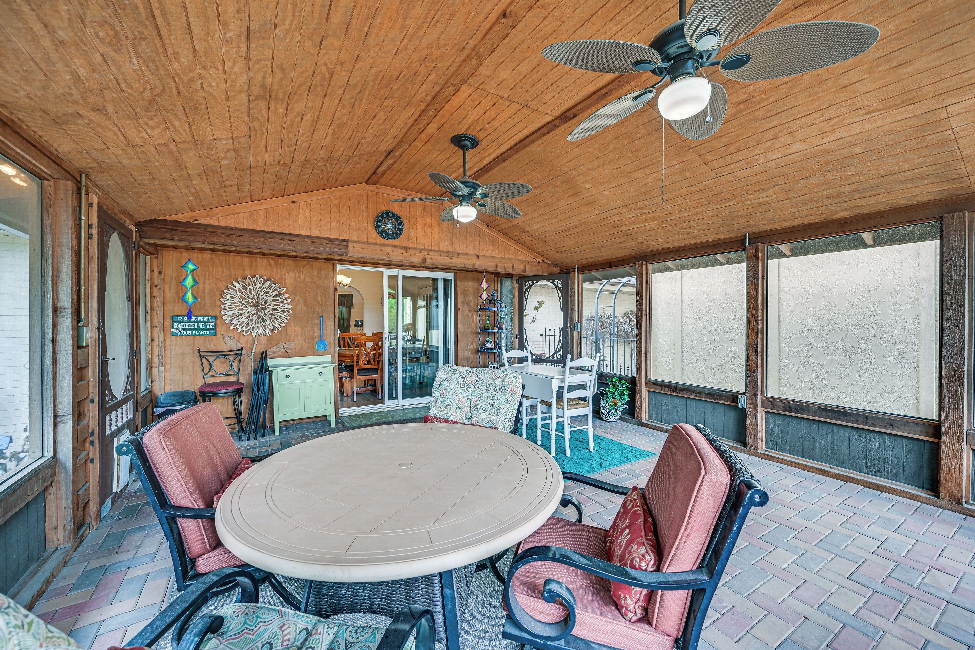 A covered patio area with a round table, chairs, and a ceiling fan.