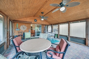 A covered patio area with a round table, chairs, and a ceiling fan.