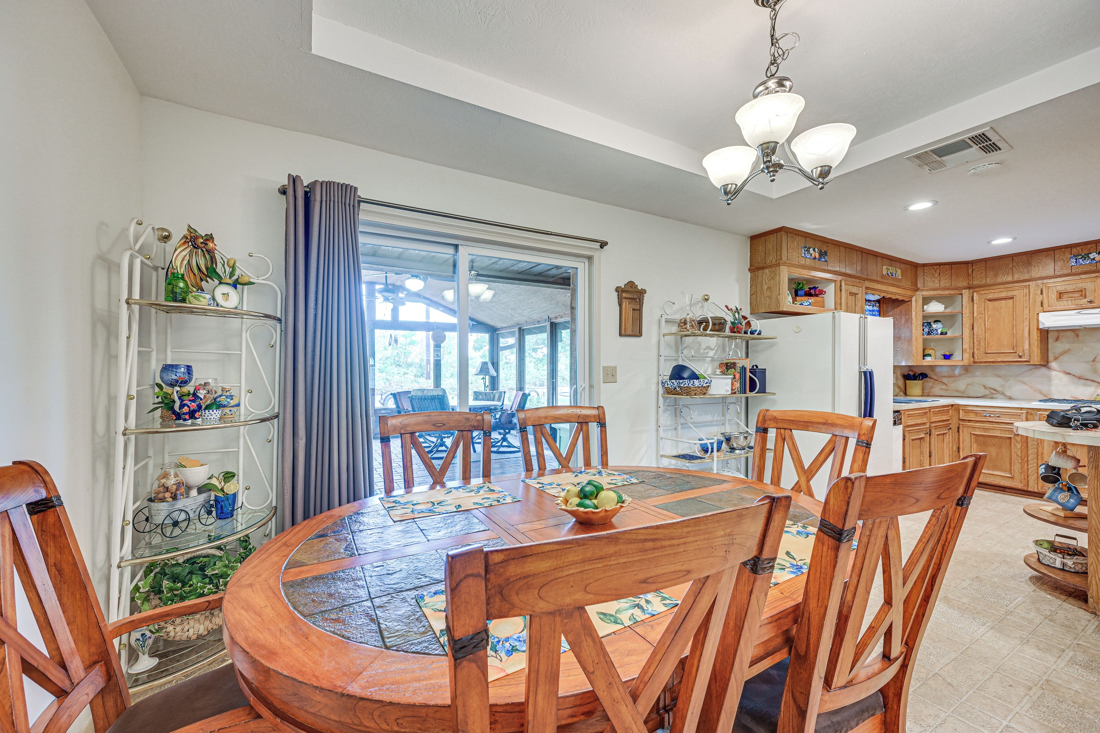 A dining area with a round wooden table, chairs, and a view through a glass door to an outdoor patio.