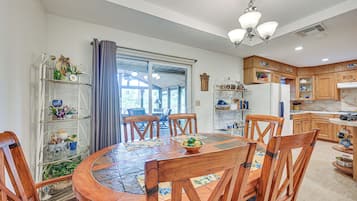 A dining area with a round wooden table, chairs, and a view through a glass door to an outdoor patio.