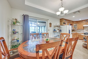 A dining area with a round wooden table, chairs, and a view through a glass door to an outdoor patio.