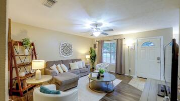 Ein Wohnzimmer mit Sofa, Sessel, Couchtisch und Deckenventilator.