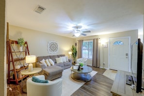 A living room with a sofa, armchair, coffee table, and a ceiling fan.