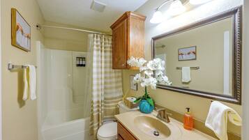 A bathroom with a shower, toilet, sink, and a large mirror.