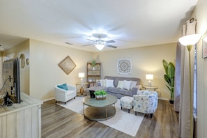 A living room with a ceiling fan, a sofa set, a coffee table, and a TV.