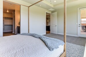 A bedroom with a bed, a closet, and a door leading to a balcony. - Mountain Views & Spa-inspired! Hurricane Home (Hurricane)