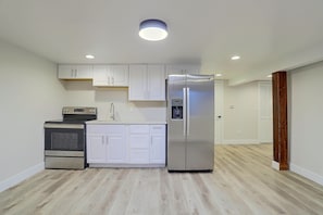A compact kitchen with white cabinets, a stainless steel refrigerator, a microwave, and an oven. - Half-acre Yard, Modern Interior! Aurora Home (Aurora)