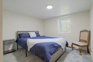 A bedroom with a bed, a nightstand, a chair, a window with blinds, and a ceiling light. - Half-acre Yard, Modern Interior! Aurora Home (Aurora)