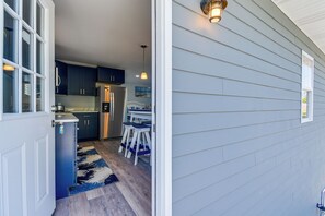 A modern kitchen with dark cabinets, a refrigerator, and a dining area with a table and chairs. - Ocean Isle Group Stay w/ 3 Private Units (Ocean Isle Beach)