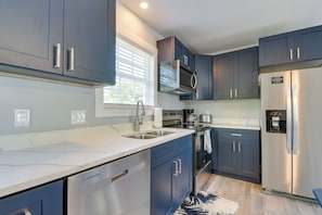 A modern kitchen with dark blue cabinets, stainless steel appliances, and a white countertop. - Ocean Isle Group Stay w/ 3 Private Units (Ocean Isle Beach)