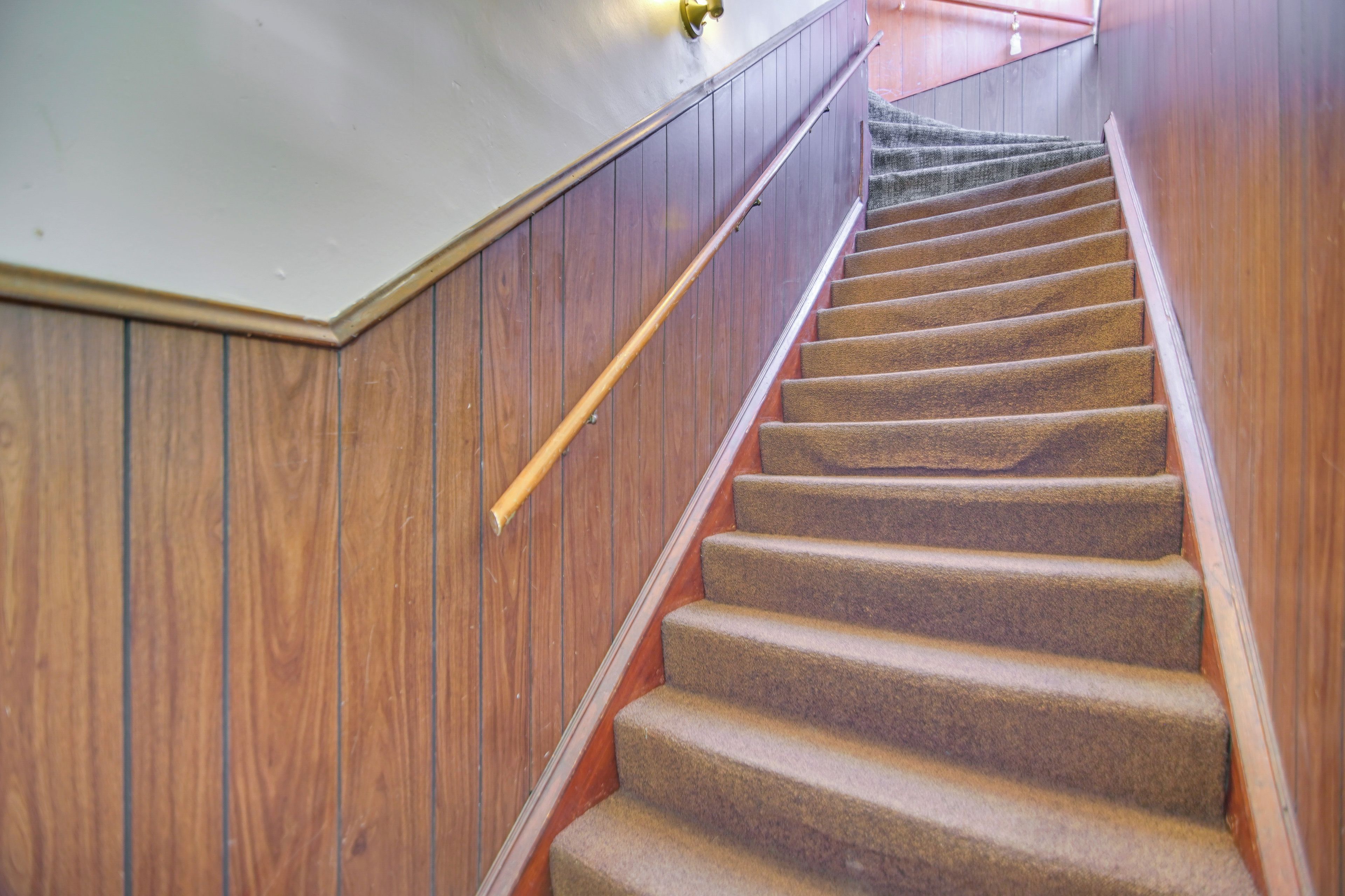 Una escalera de madera con peldaños alfombrados que suben.