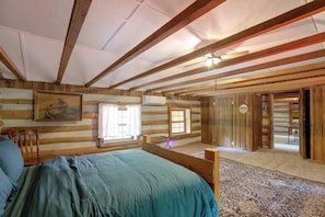 A log cabin room with a bed, two windows, a door, and a mirror. - Across From Marina! Lake Seminole Fishing Lodge (Bainbridge)