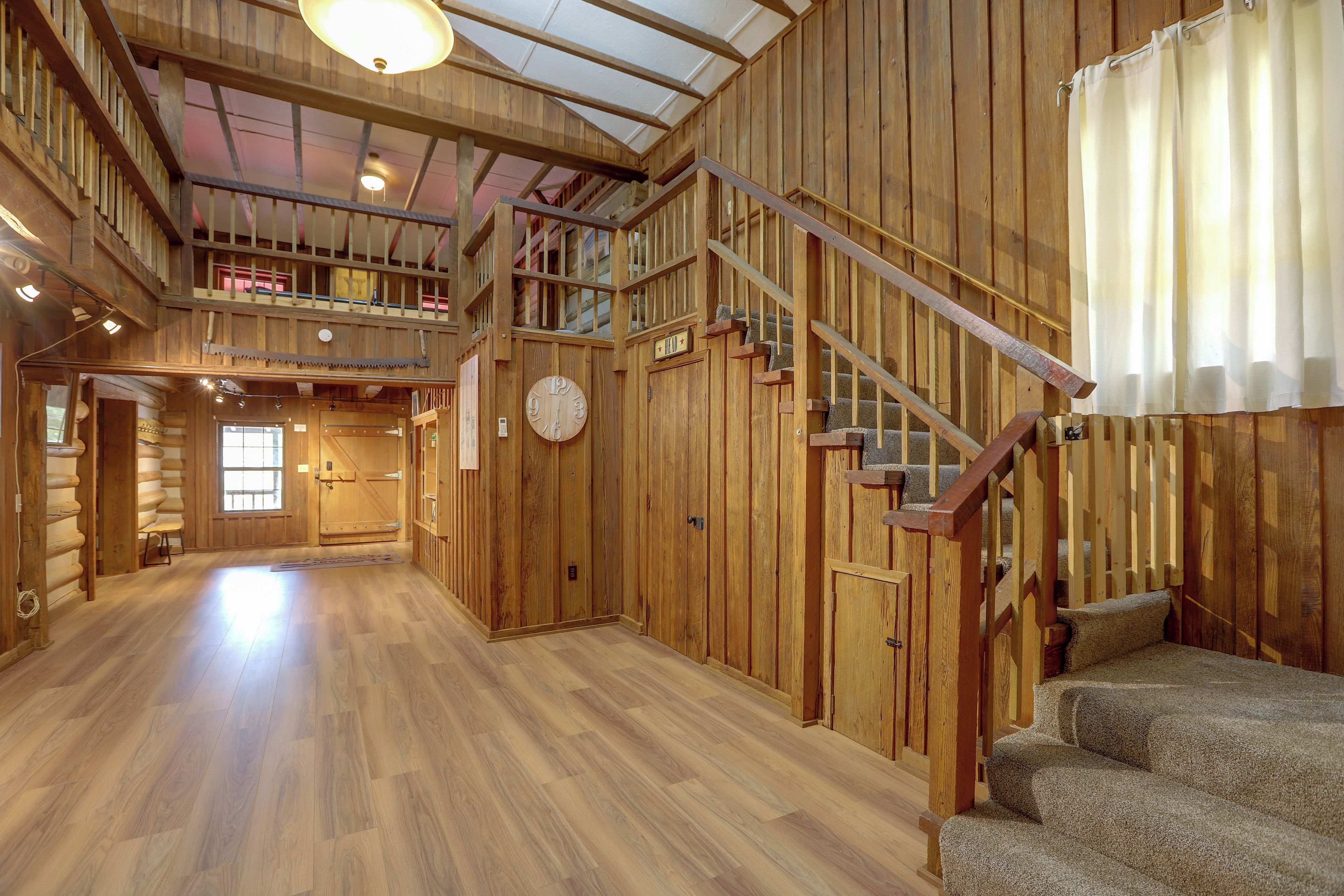 A spacious interior with wooden walls, a staircase, and a large clock.