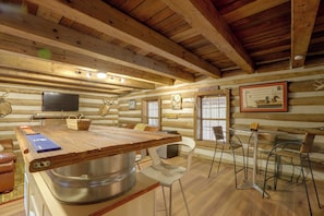 A rustic log cabin interior with a wooden dining table, chairs, a television, and a sign reading 'Lunker Lounge'. - Across From Marina! Lake Seminole Fishing Lodge (Bainbridge)