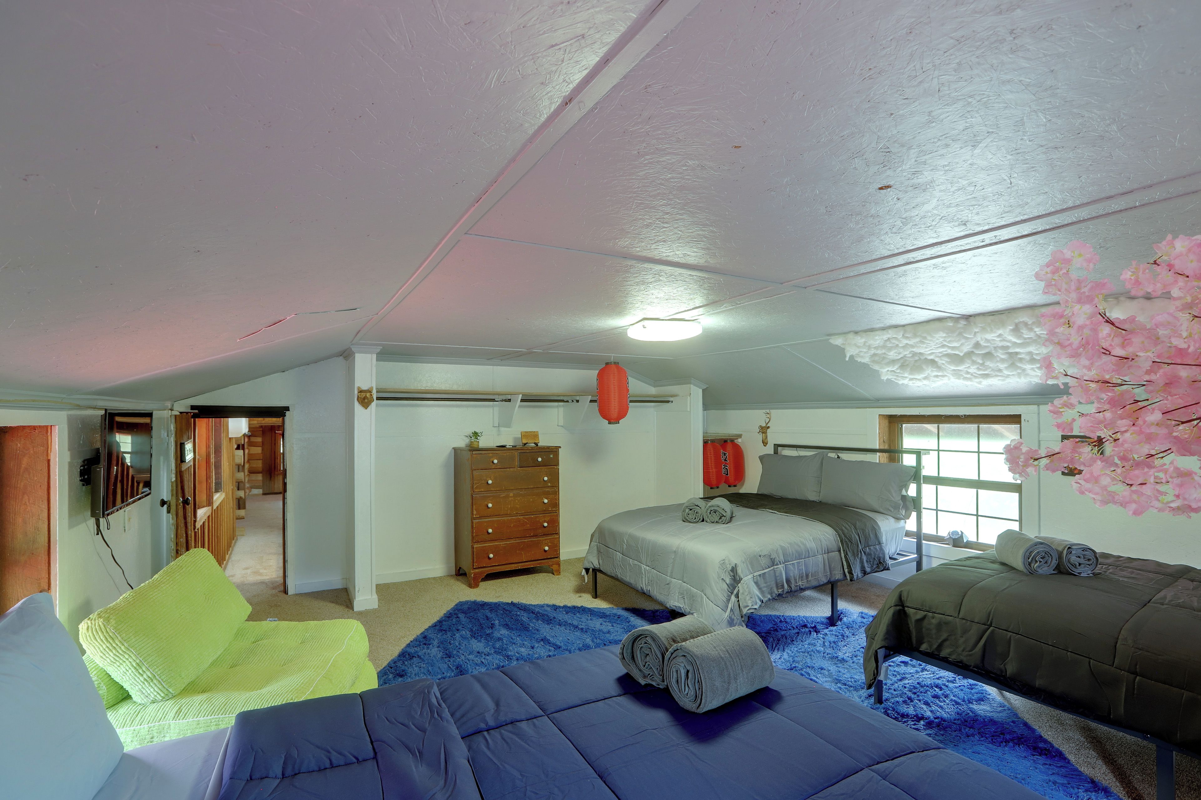 A bedroom with a bunk bed, a desk, a dresser, and a window with a view.
