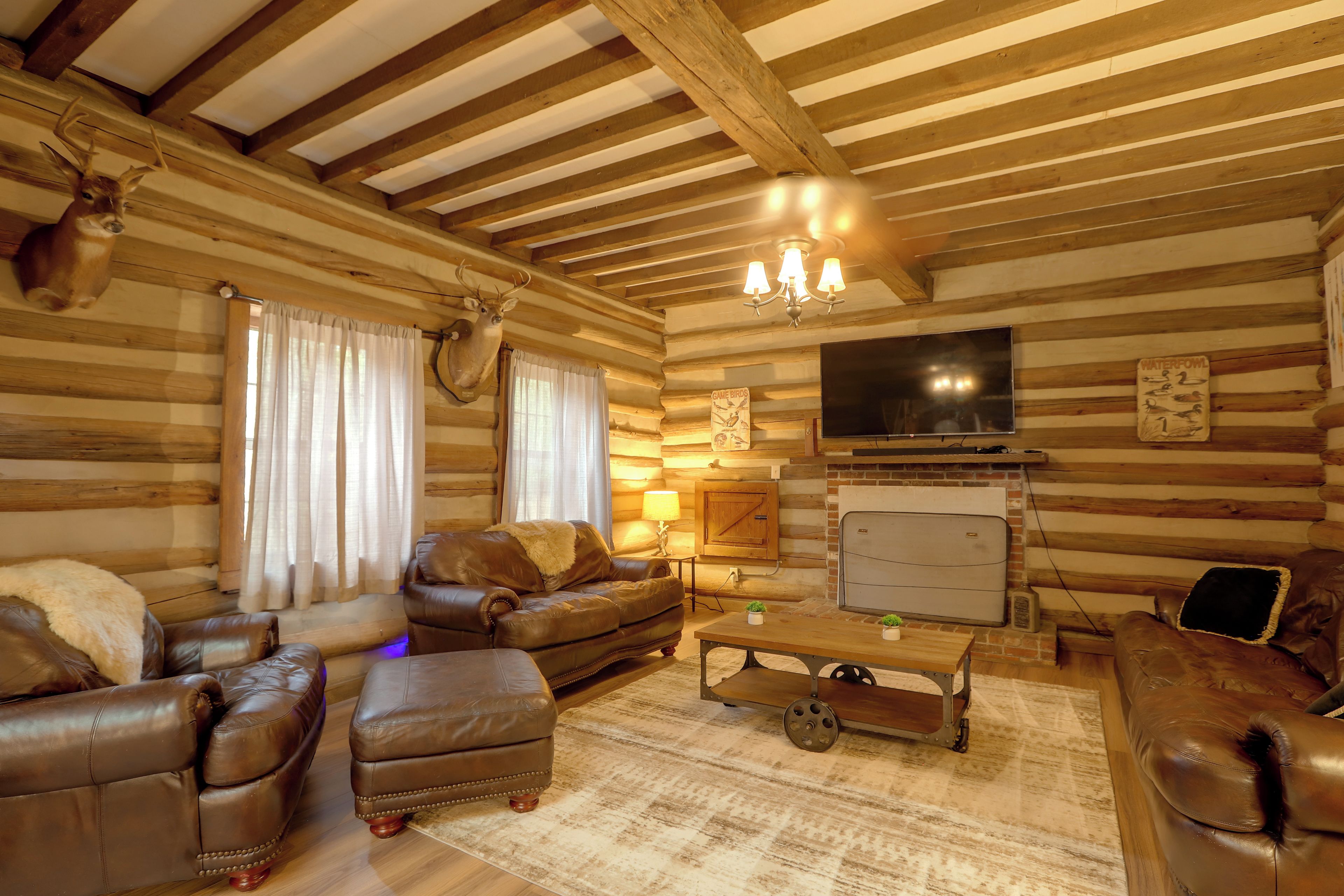 Een houten blokhut interieur met een leren zithoek, een televisie en een kroonluchter.