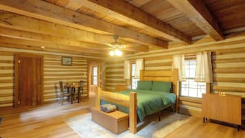 A log cabin bedroom with a bed, a wooden desk, and a chair.