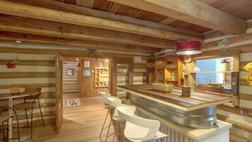 Un interno rustico in legno con zona bar, sgabelli da bar e soffitto in legno.