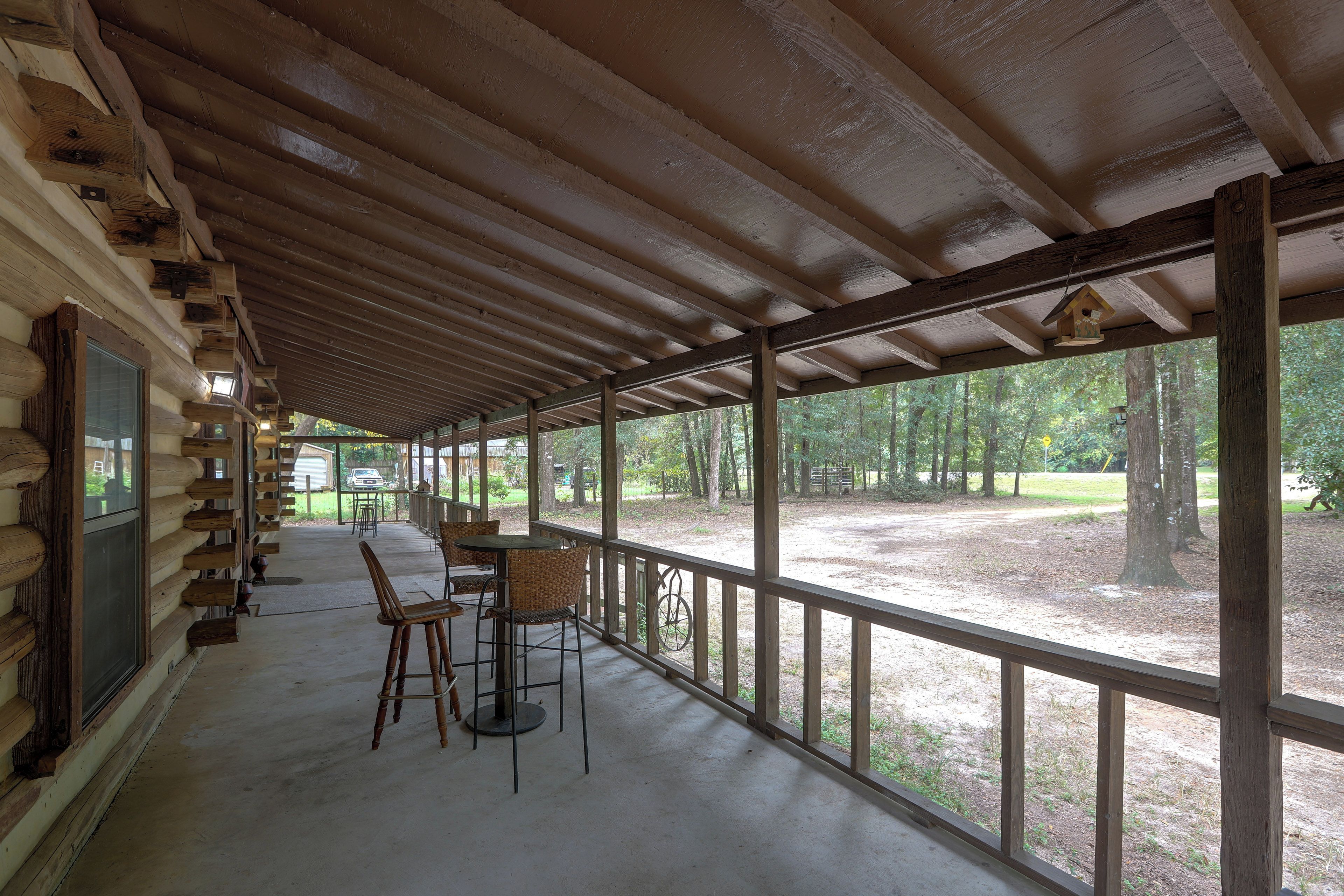 A covered outdoor area with a concrete floor, wooden benches, and a table.