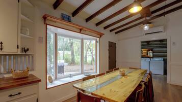 A dining area with a large wooden table, chairs, and a window with a view of the outdoors.