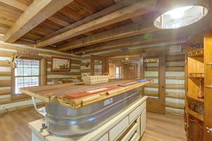 A rustic wooden cabin interior with a central bar area, wooden walls, and a ceiling with exposed beams.