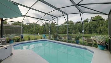 Una piscina exterior cubierta con sillas de descanso y plantas en macetas.