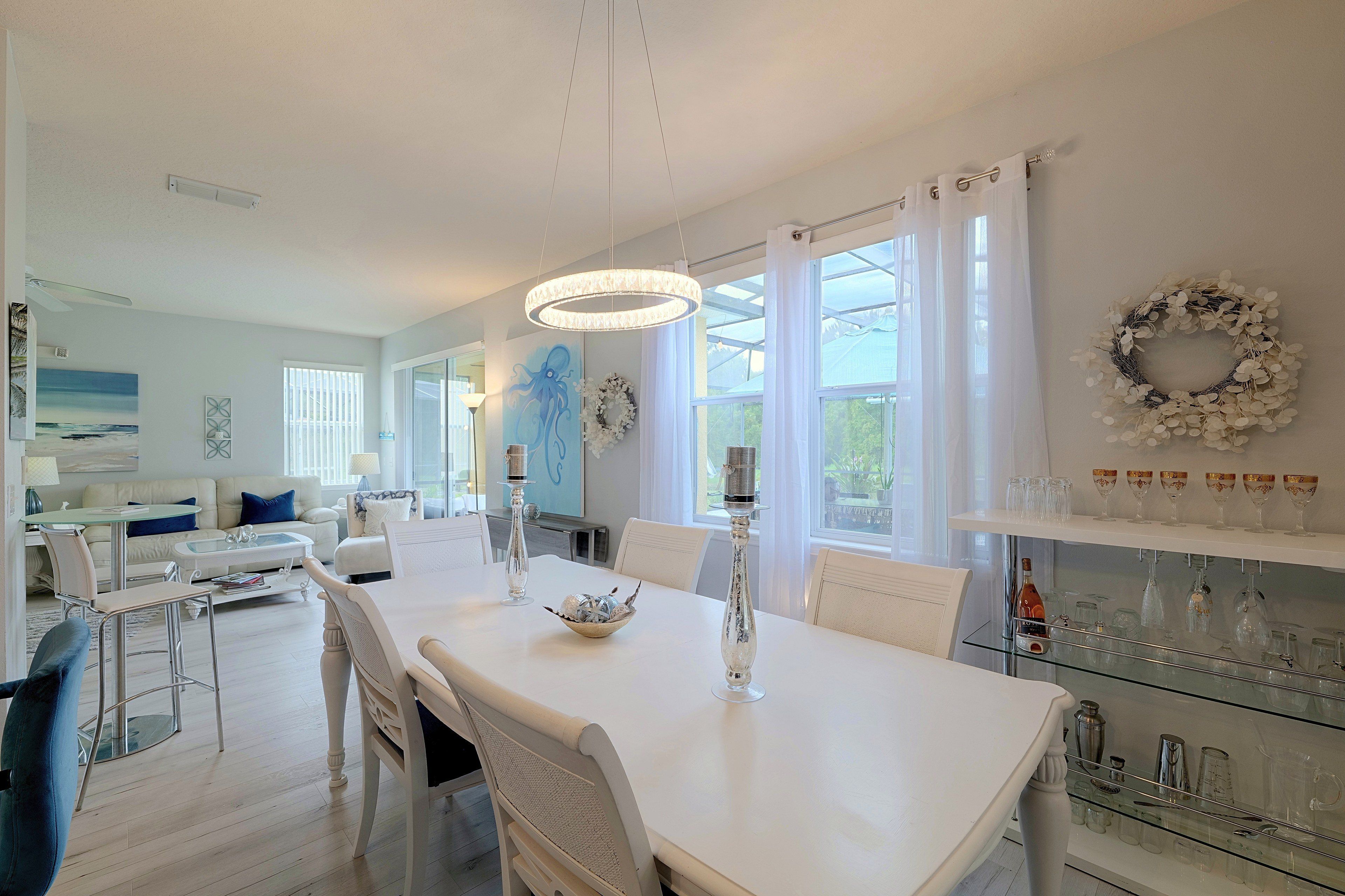 Un comedor moderno con una mesa blanca, sillas y una lámpara de araña.