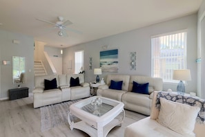 A living room with a sofa, coffee table, and a ceiling fan. - Lanai, Pool & Patio Bar! Spacious Home Near WDW (Davenport)