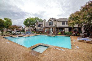 A rectangular swimming pool with a diving board, surrounded by lounge chairs and a covered patio area. - 5 Mi to Toyota Music Factory! Unit w/ Pool Access (Irving)