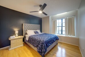 A bedroom with a bed, nightstand, lamp, ceiling fan, and a window with curtains. - 5 Mi to Toyota Music Factory! Unit w/ Pool Access (Irving)