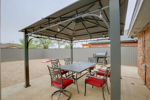 An outdoor patio with a covered seating area, a table, and chairs. - The Iola / Chic Vintage Glam & Modern Comfort (Lubbock)