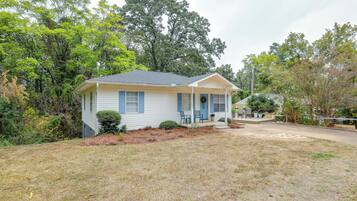 A single-story house with a front porch, a small garden, and a driveway.