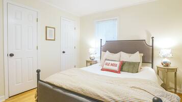 A bedroom with a bed, bedside tables, a lamp, and a framed quote on the wall.