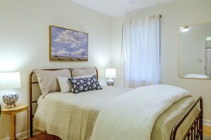A bedroom with a bed, two bedside tables, a lamp, a painting, and a window with curtains. - Game Day Base! 1 Mi to Ole Miss & Oxford Square (Oxford)