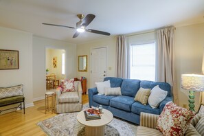 A living room with a blue sofa, striped armchairs, a coffee table, a ceiling fan, and a dining area with a table and chairs. - Game Day Base! 1 Mi to Ole Miss & Oxford Square (Oxford)