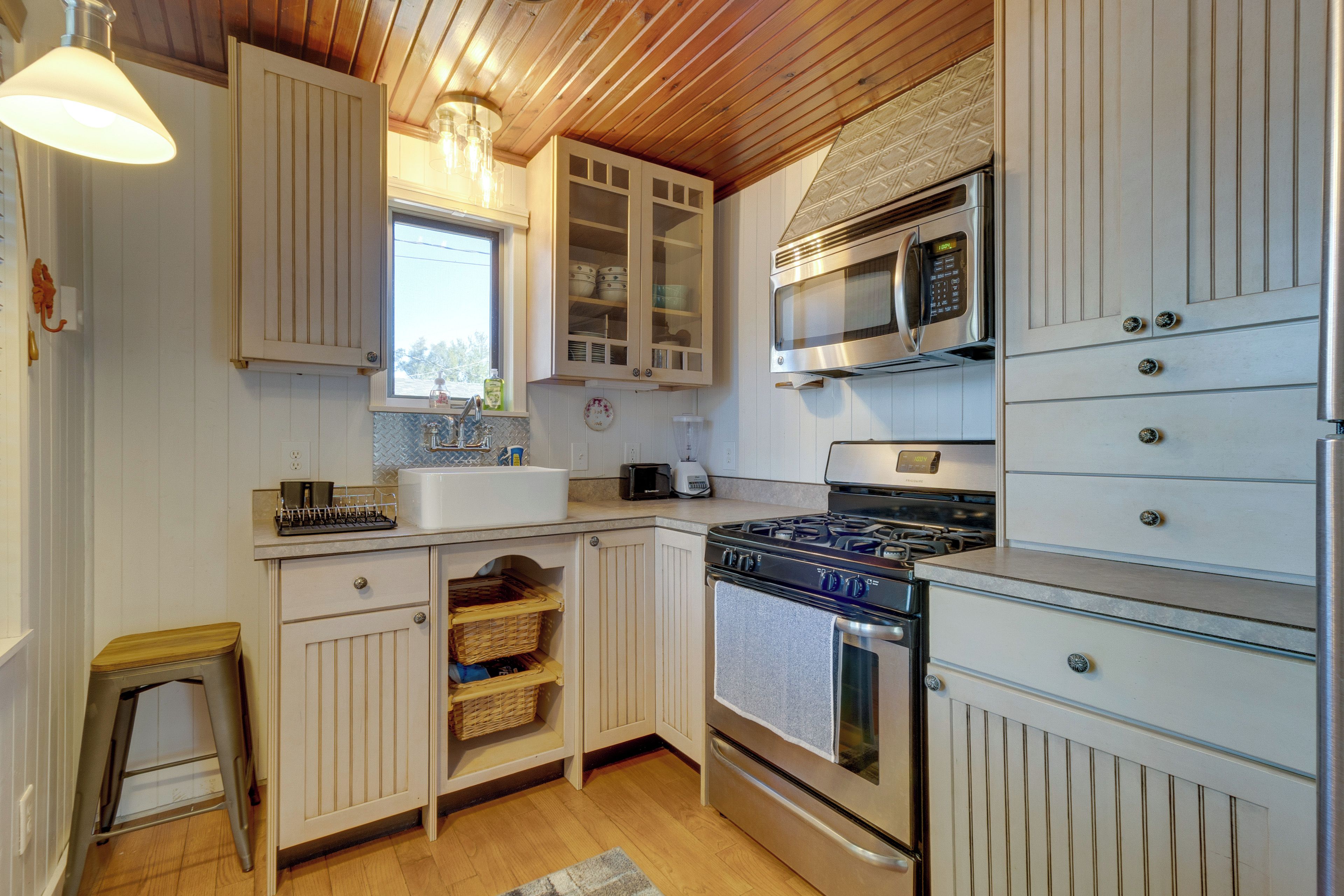 Una cocina con armarios de madera, microondas, estufa y pileta.