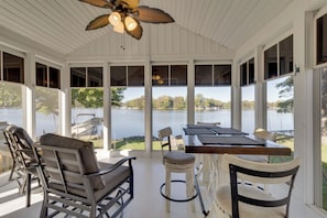 Un espace extérieur abrité, aménagé avec des chaises et une table, et offrant une vue sur un lac.
