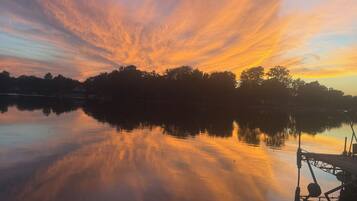 A calm lake at sunset with a dock on the right.