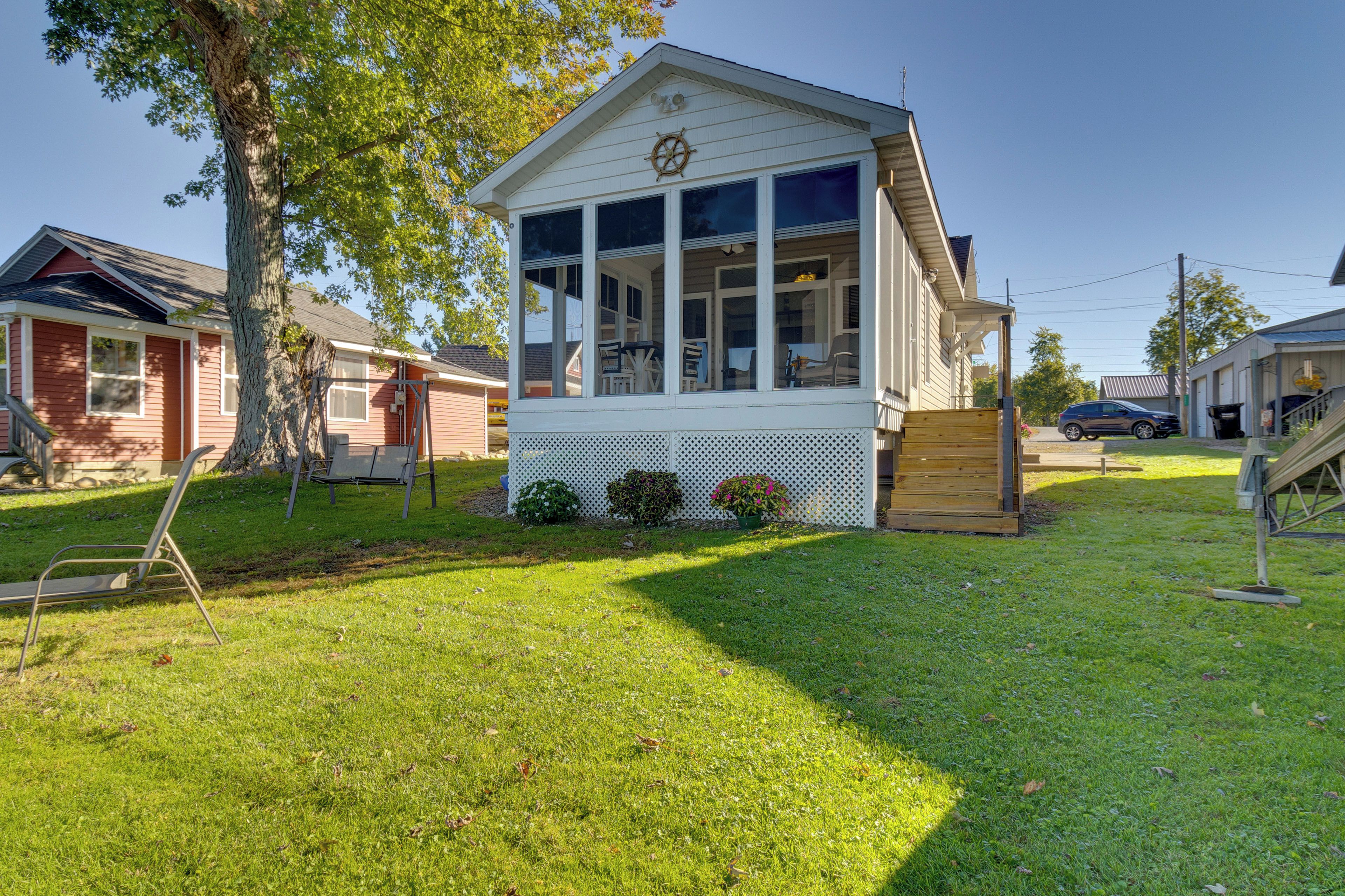 A small, single-story building with a white exterior, large windows, and a small porch area.