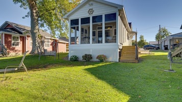 A small, single-story building with a white exterior, large windows, and a small porch area.
