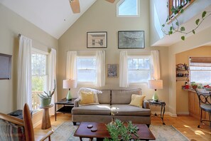 A living room with a sofa, two side tables with lamps, a coffee table, and a plant. There are windows with curtains, a ceiling fan, and artwork on the walls. - Misty Mountain, Peaceful Mountain Retreat (Marshall)