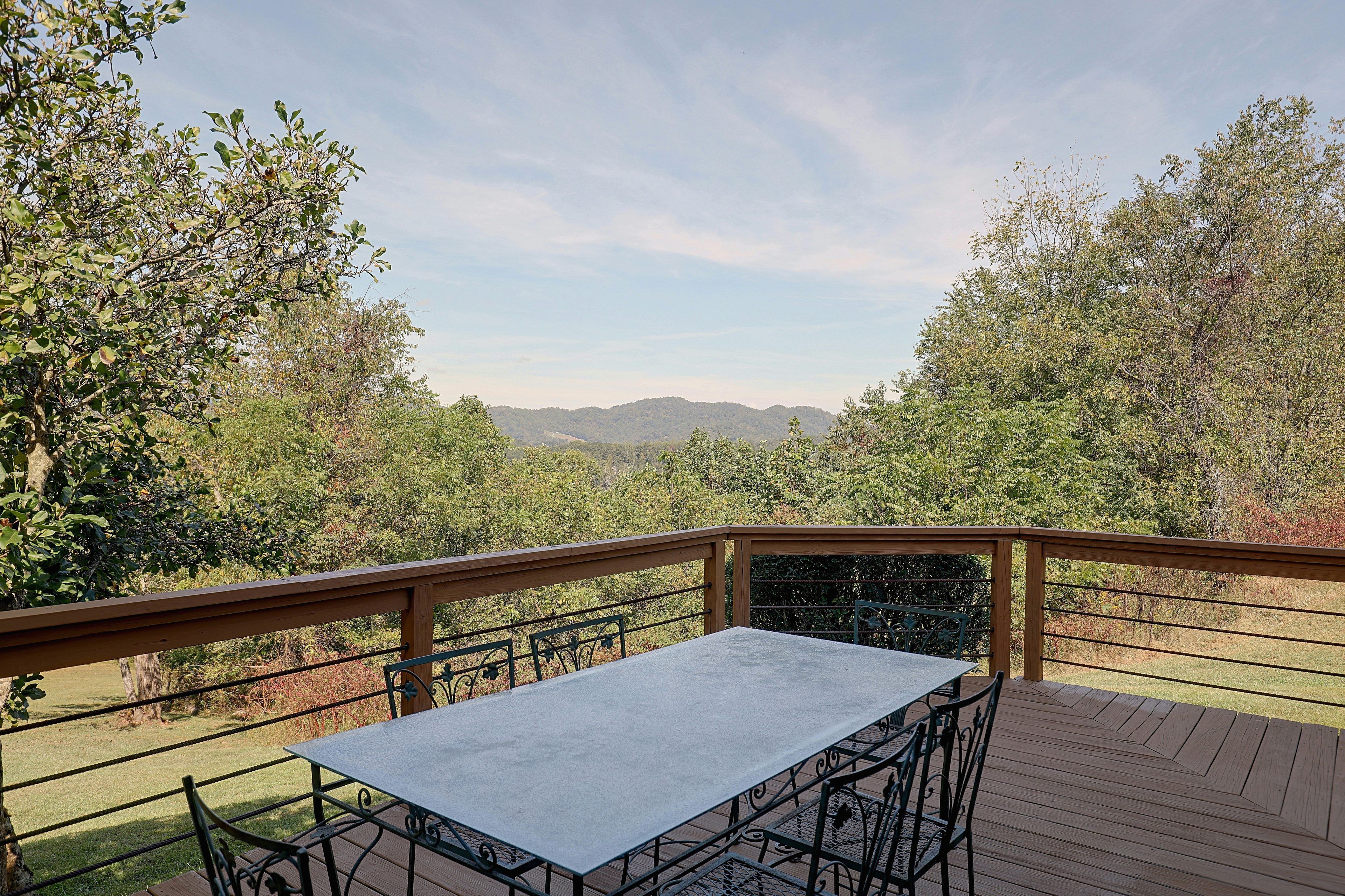 A deck with a table and chairs, overlooking a mountainous landscape.