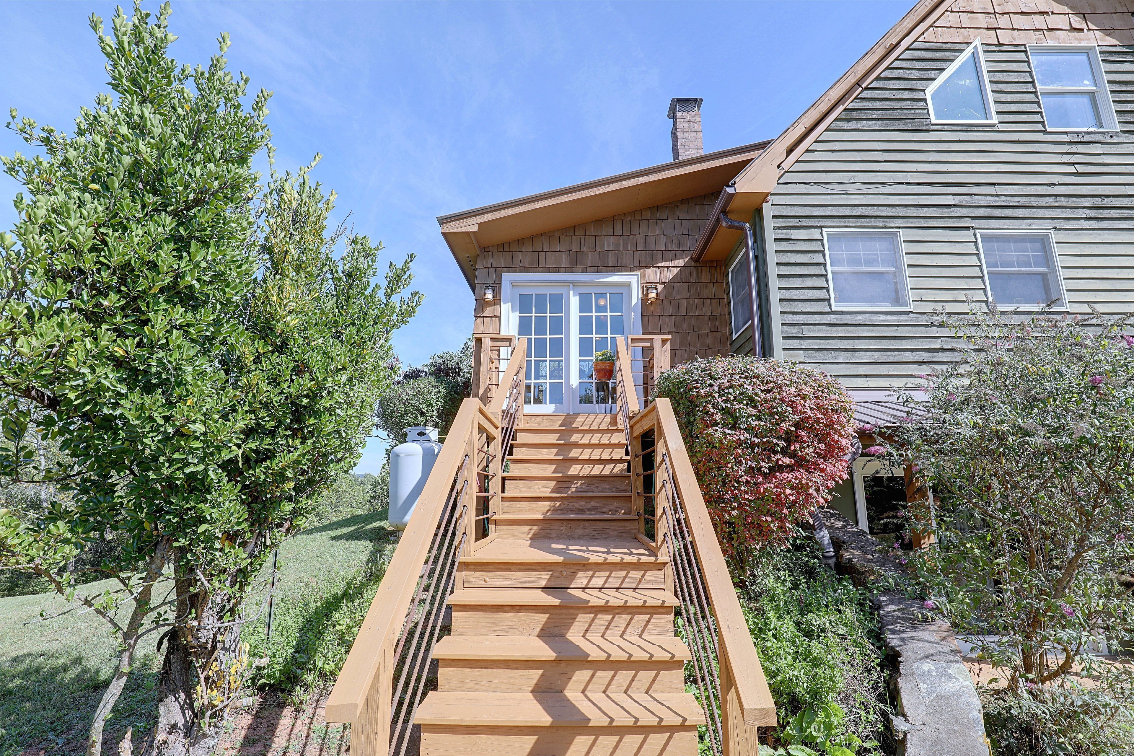 A wooden staircase leading to a house with a white door and windows.