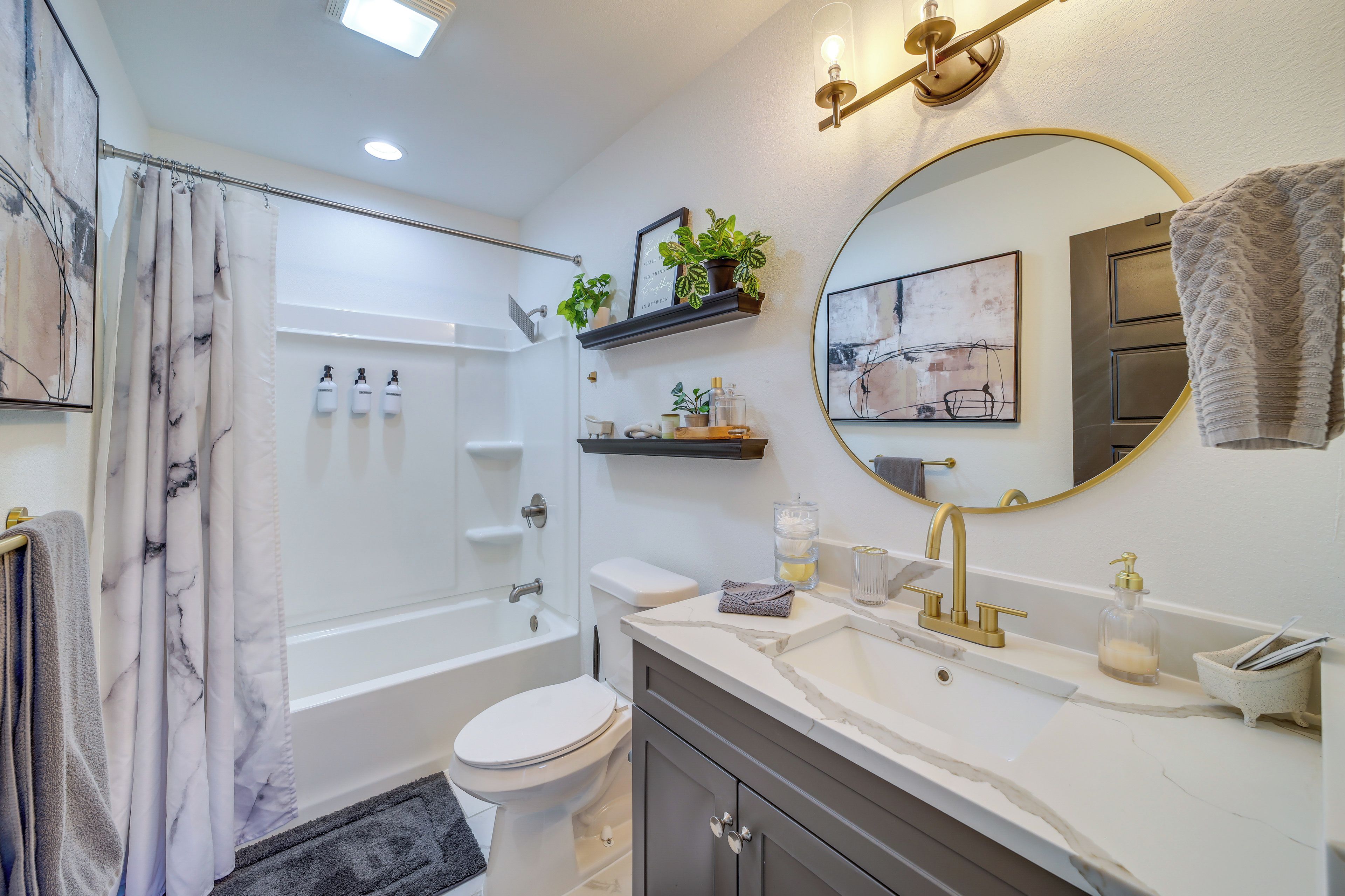 A modern bathroom with a bathtub, toilet, and vanity.