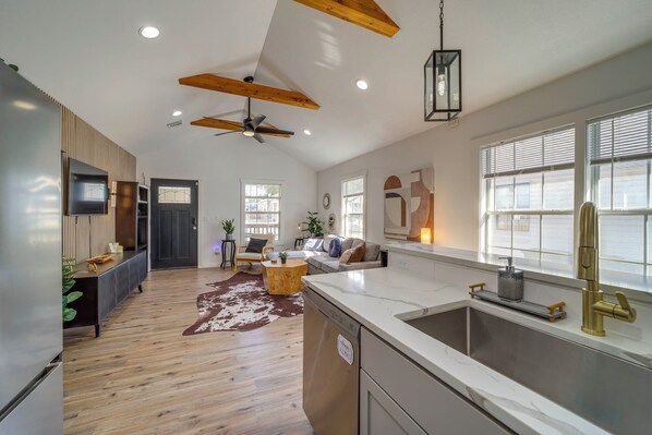 A spacious kitchen with a large island, modern appliances, and a window with blinds.