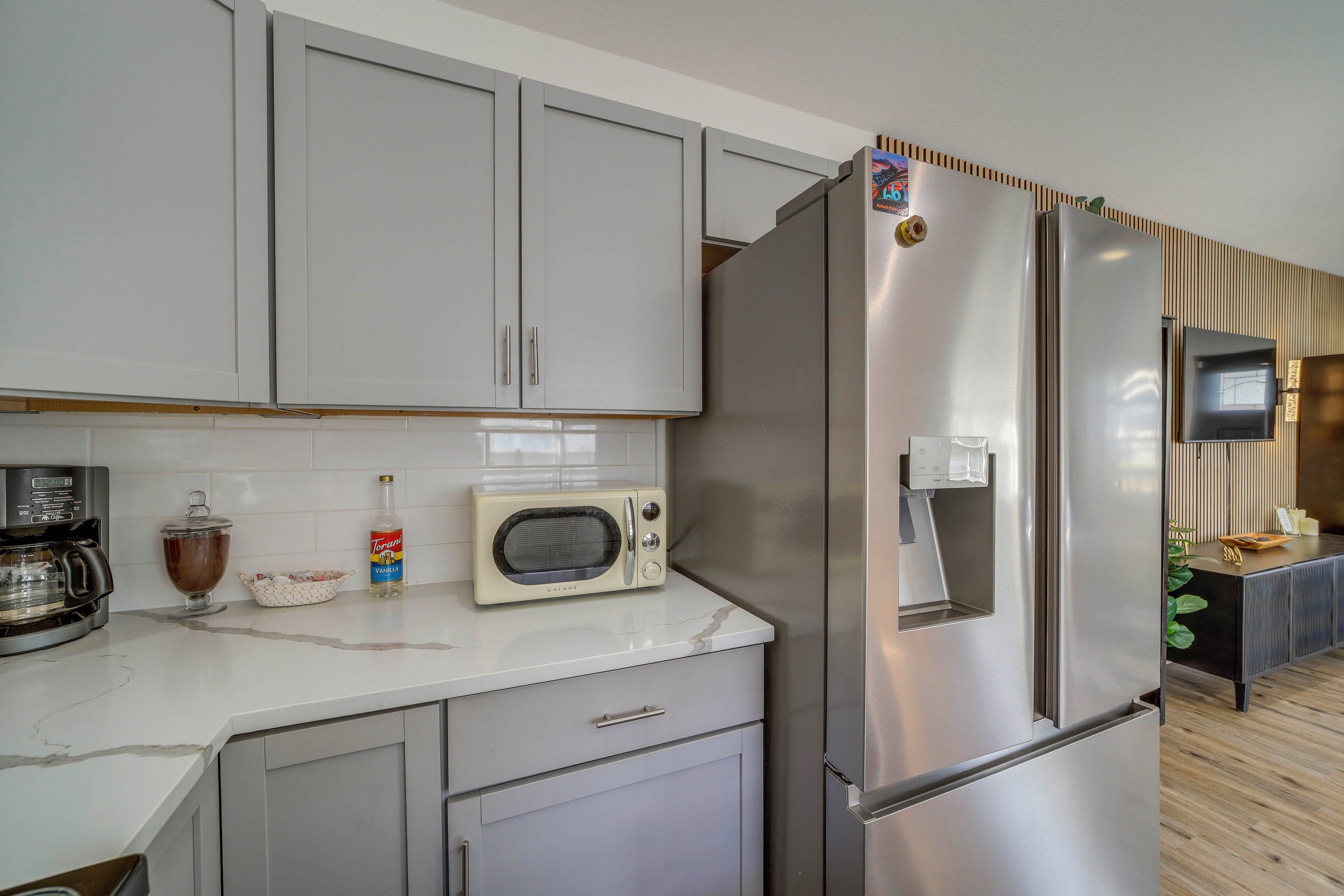Una cocina moderna con un refrigerador de acero inoxidable, un microondas y una cafetera.
